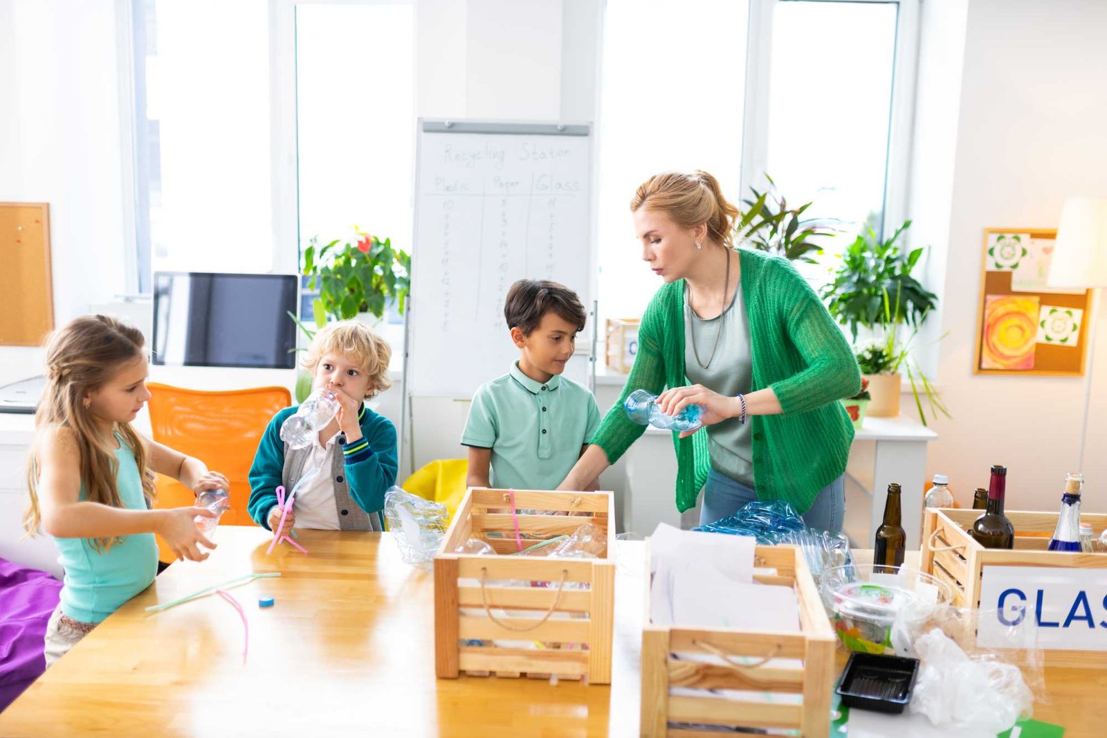 Schoolchildren and teacher sorting litter in spacious classroom